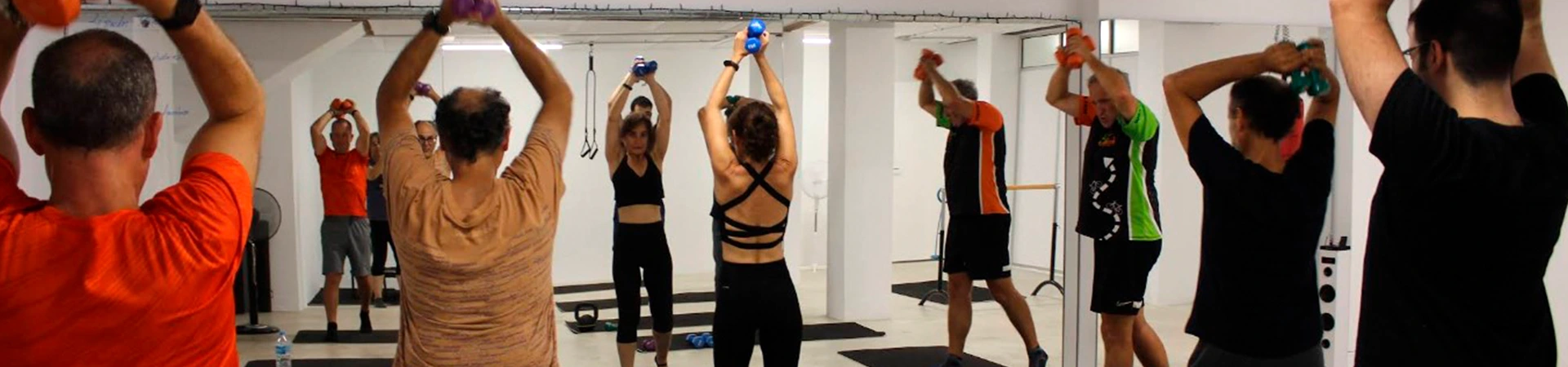 mujer con mancuernas dirigiendo grupo hombres